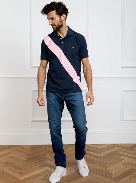Man wearing navy 100% cotton polo shirt with pale pink sash detail and Newmarket 875 horse logo embroidered on the front.
